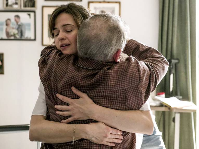 eine junge Frau umarmt einen alten Mann